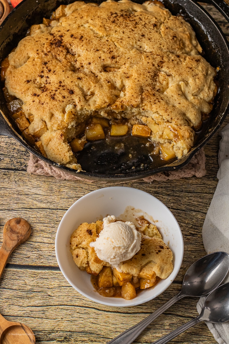 apple cobbler topped with cake like topping with caramel apple filling in a cast iron skillet