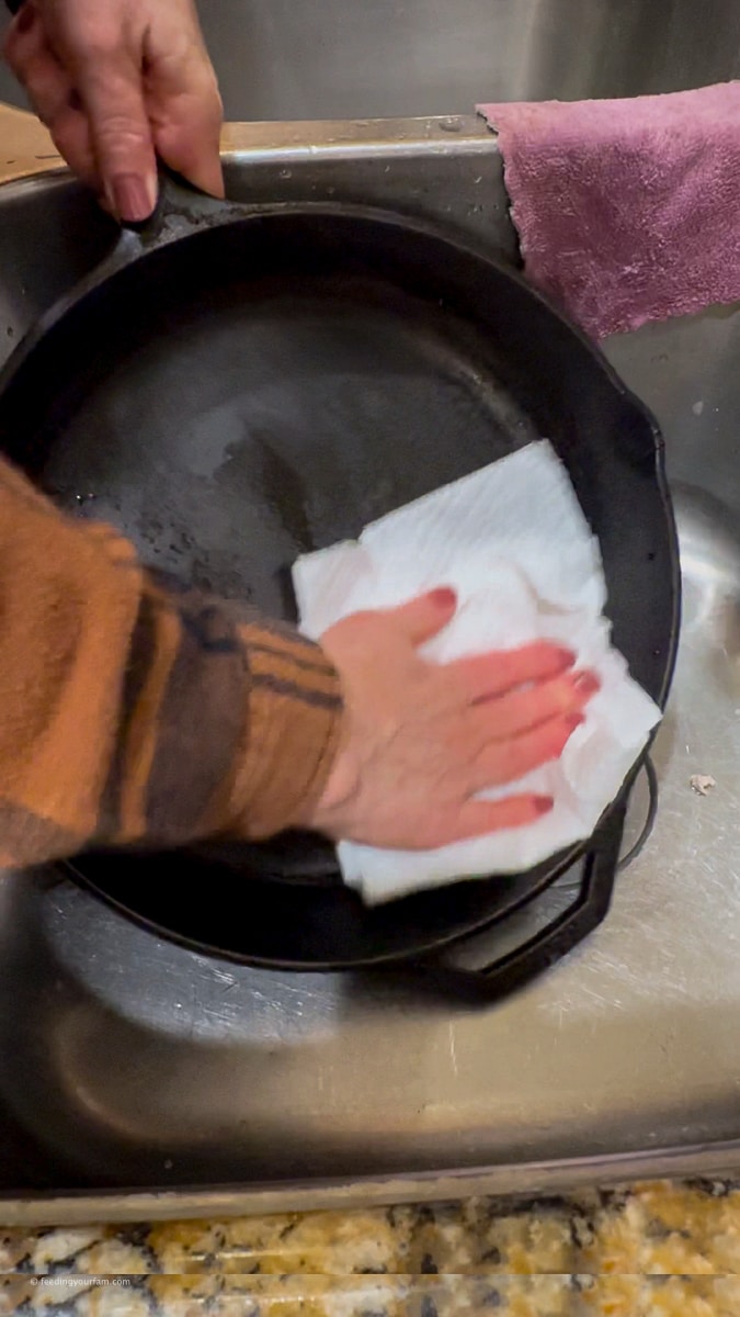drying a cast iron skillet with a paper towel