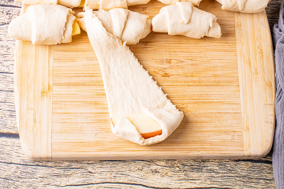 wrapping apple slices in crescent roll dough to make apple dumplings