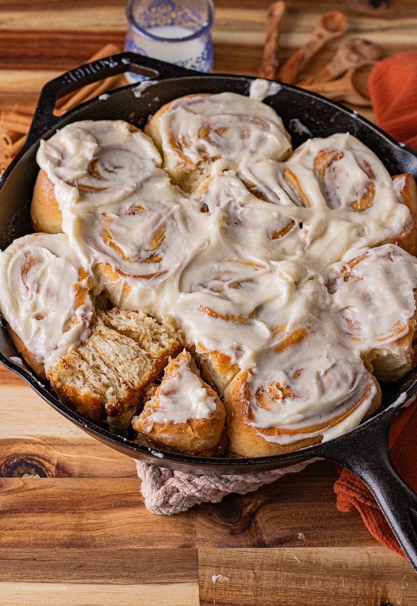 homemade cinnamon rolls baked in a cast iron skillet with cream cheese frosting