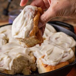 cast iron cinnamon rolls with cream cheese frosting baked in a skillet