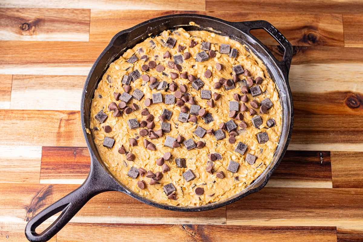 uncooked pumpkin oatmeal chocolate chip cookie in a cast iron skillet 